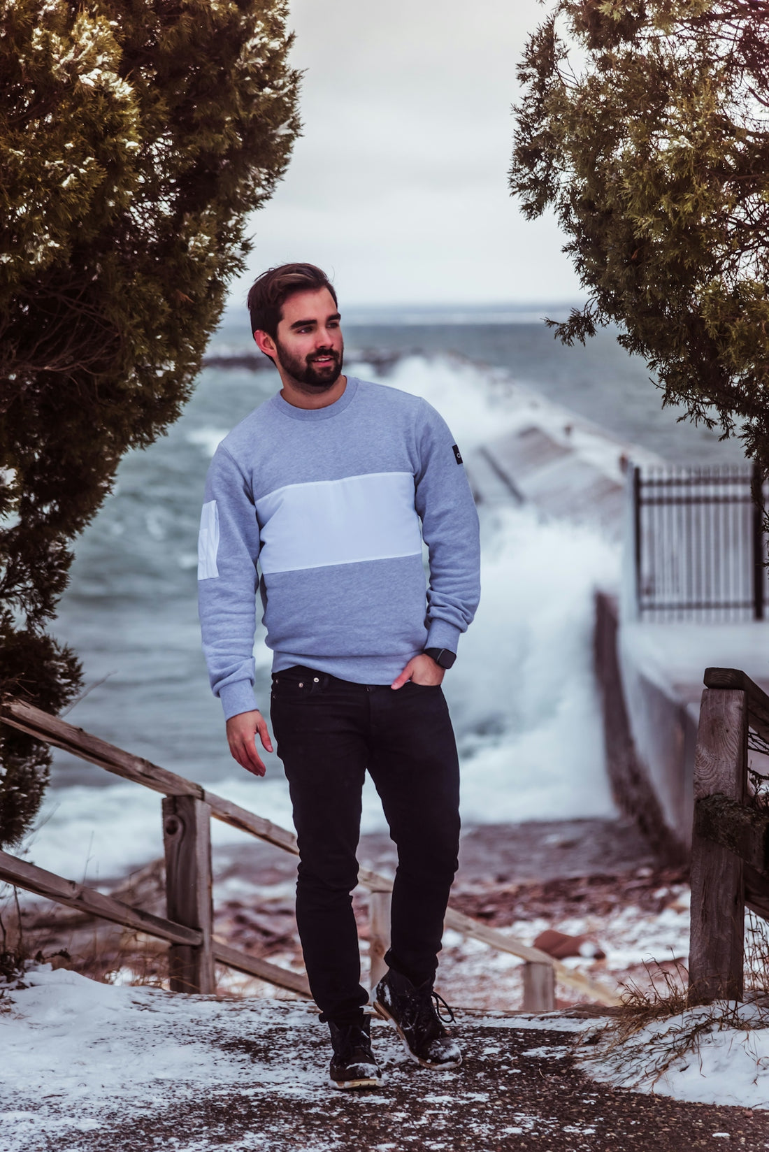 a man in a blue sweater standing on a snowy path