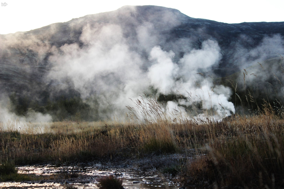 Steam rises from the ground near a mountain