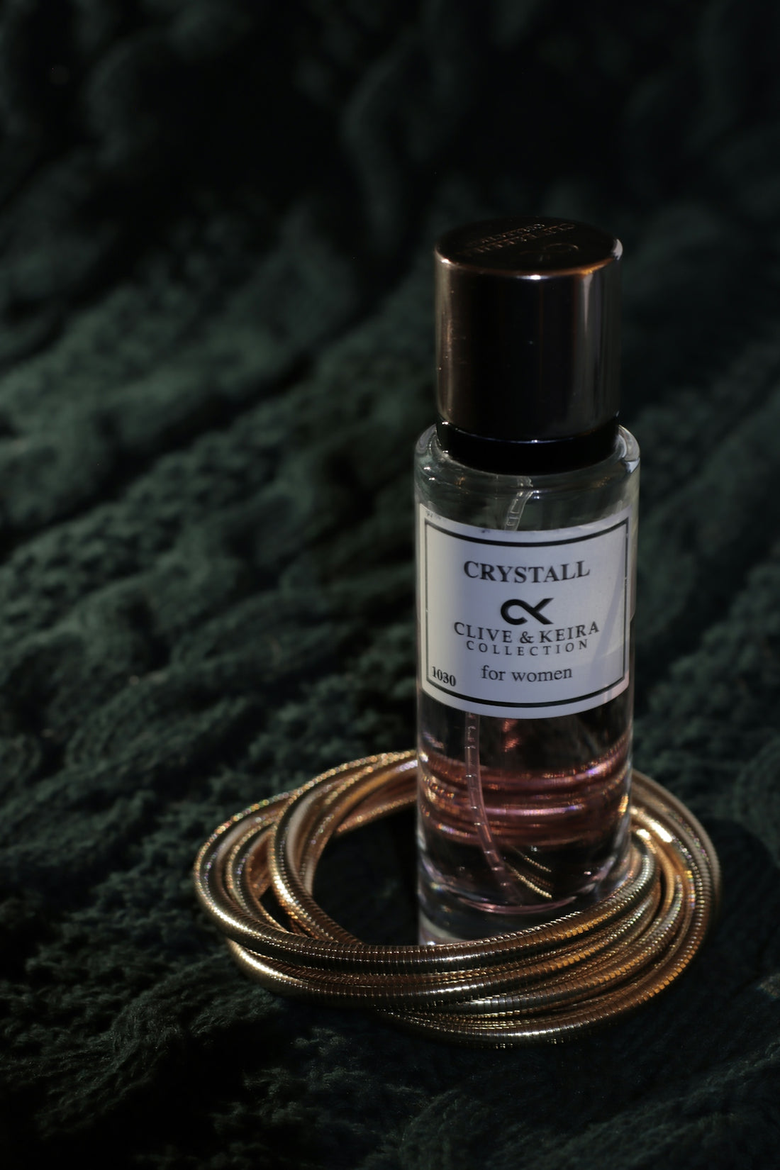 A bottle of perfume sitting on top of a green blanket