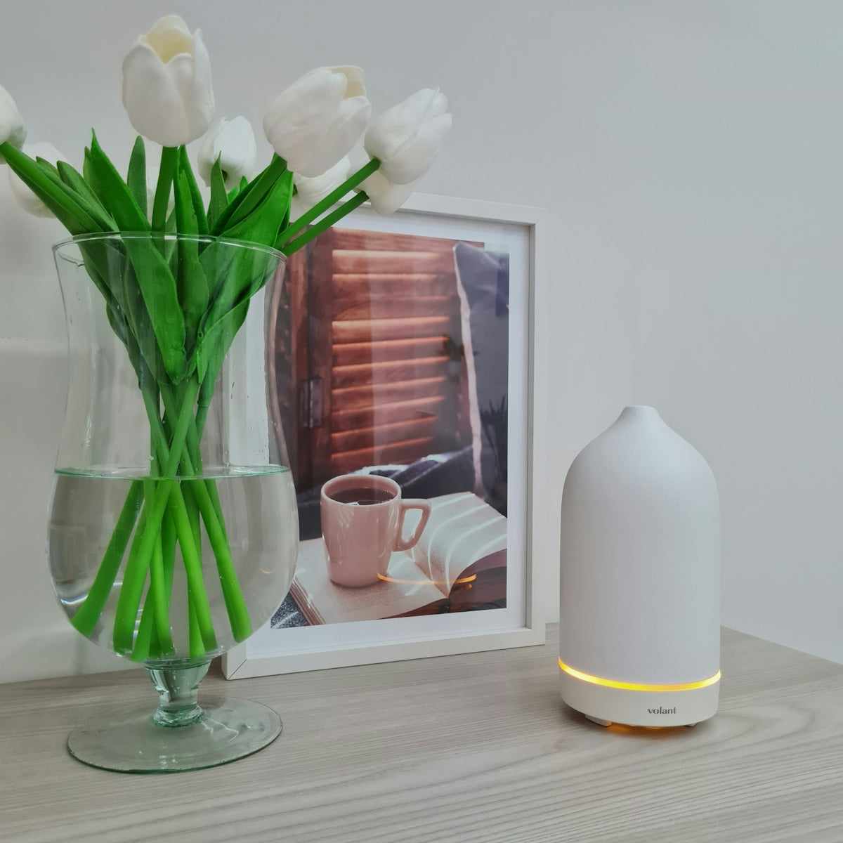 a vase of tulips next to a picture of a coffee cup