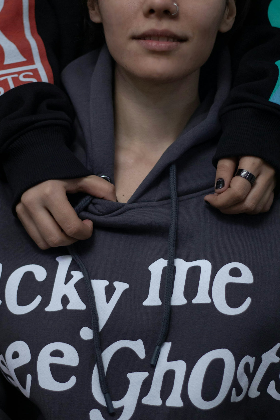a woman in a black hoodie with a ring on her finger