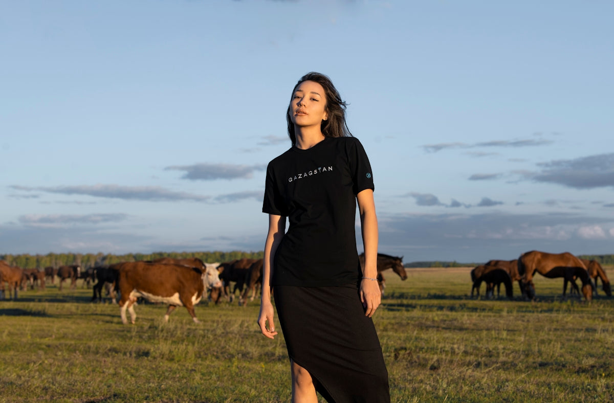 a person standing in a field with cows in the background