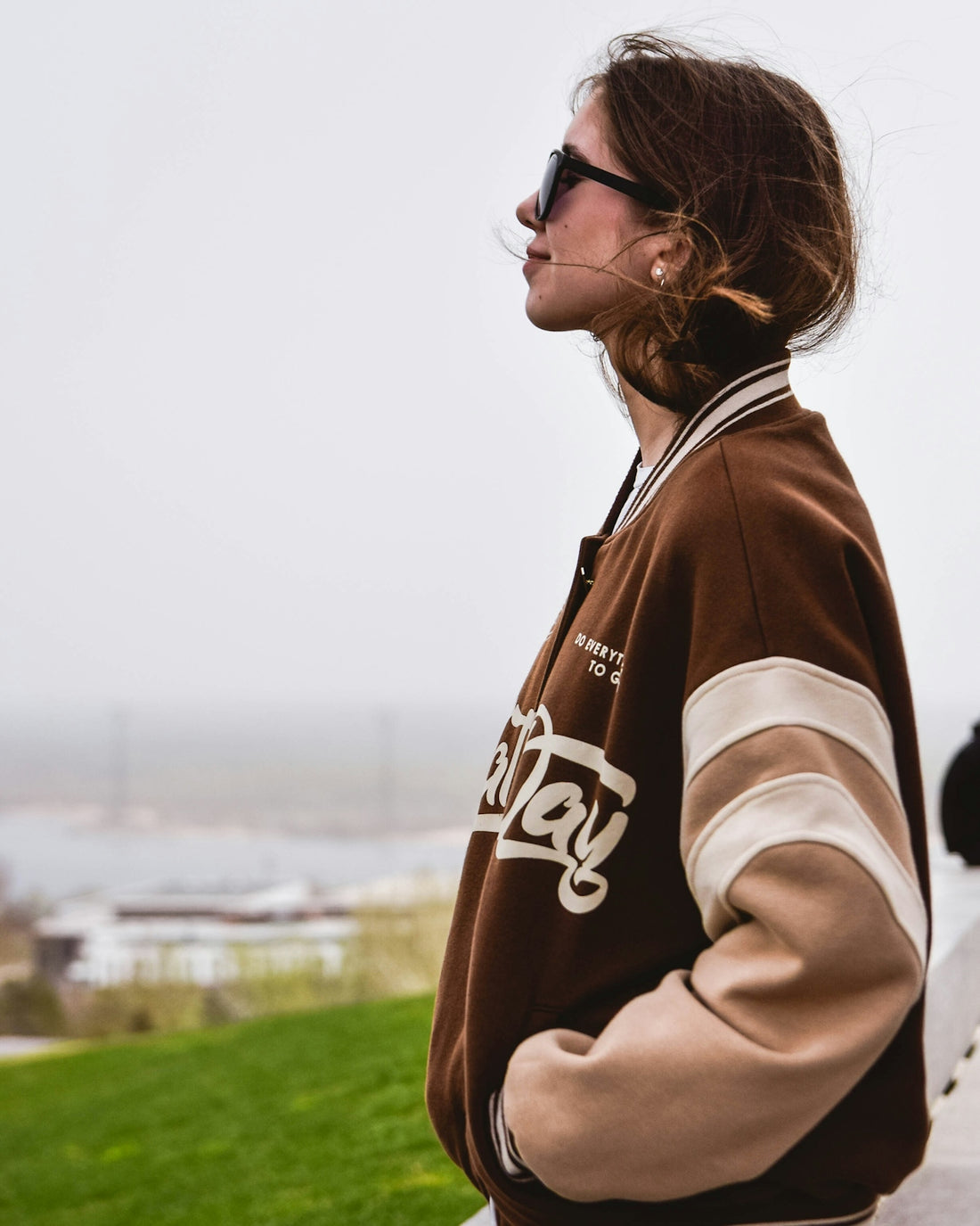 a woman wearing a brown and white jacket and sunglasses
