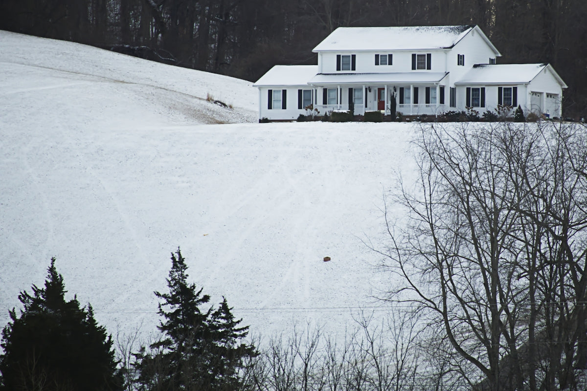 A large white house sitting on top of a snow covered hill